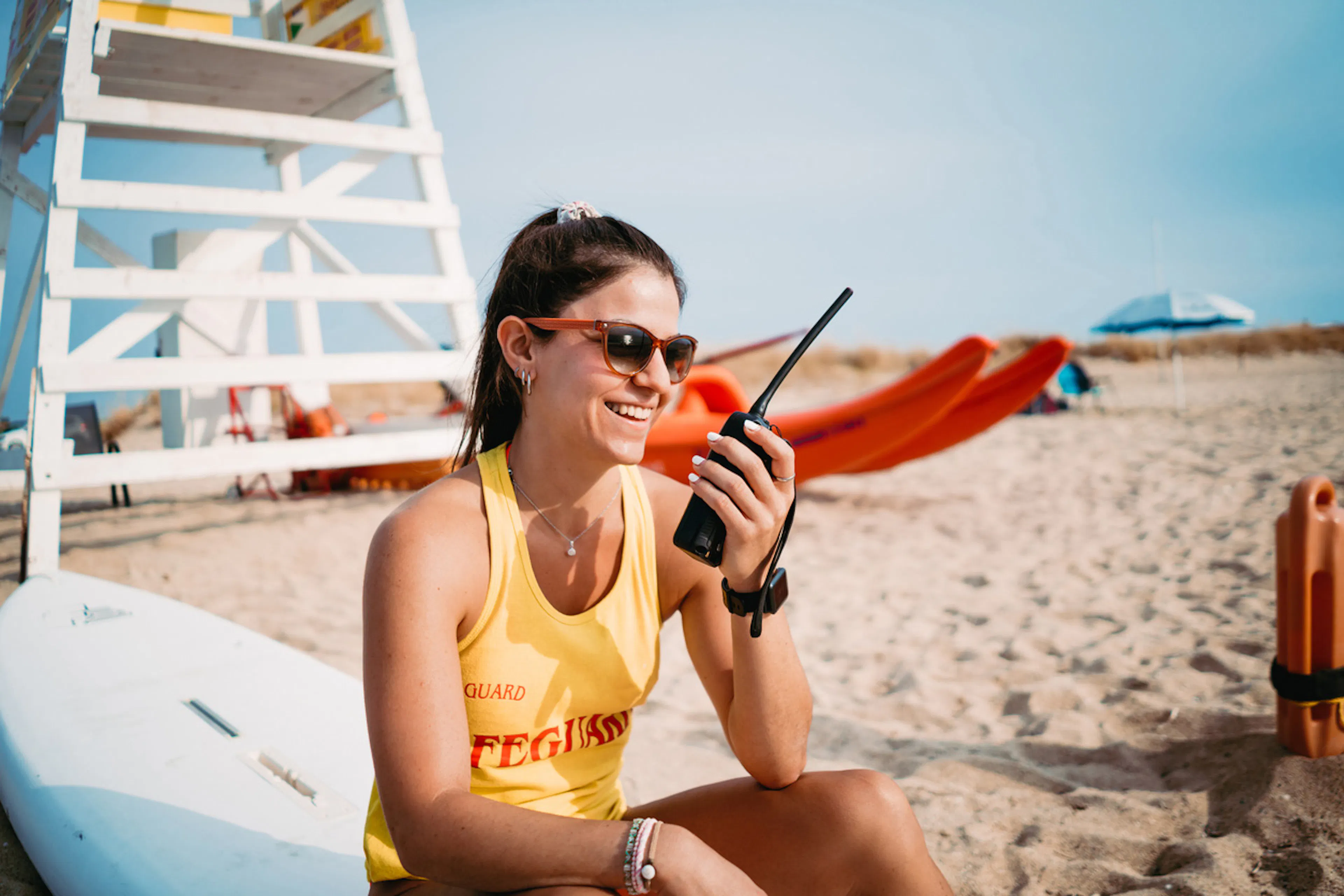 female lifeguard on beach talking into a walkie talkie