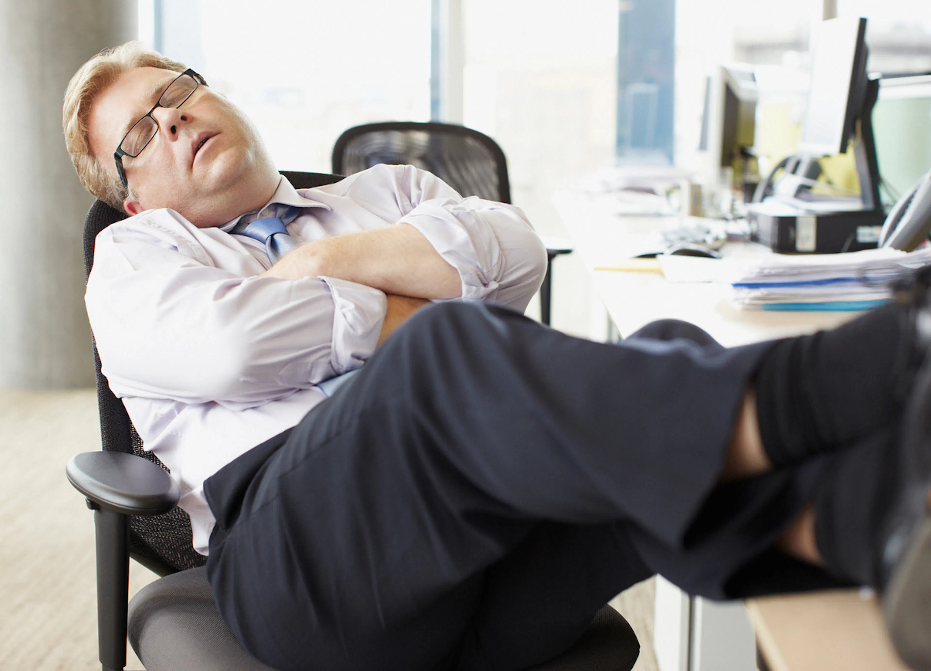 businessman napping at desk with feet up and arms crossed