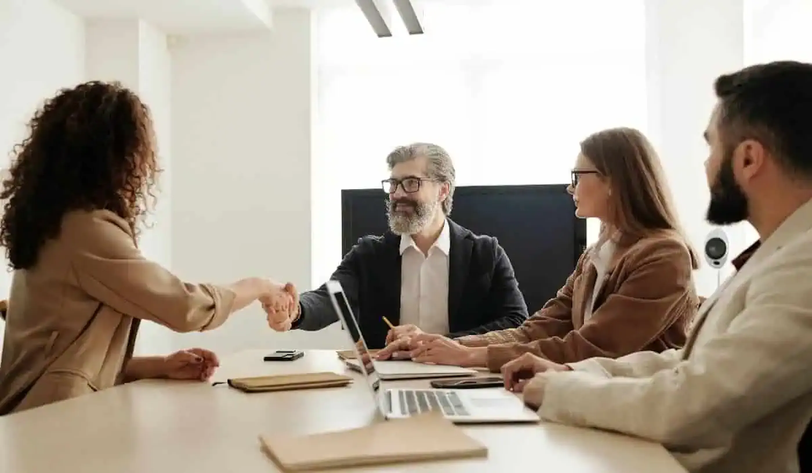 people shaking hands across a conference table