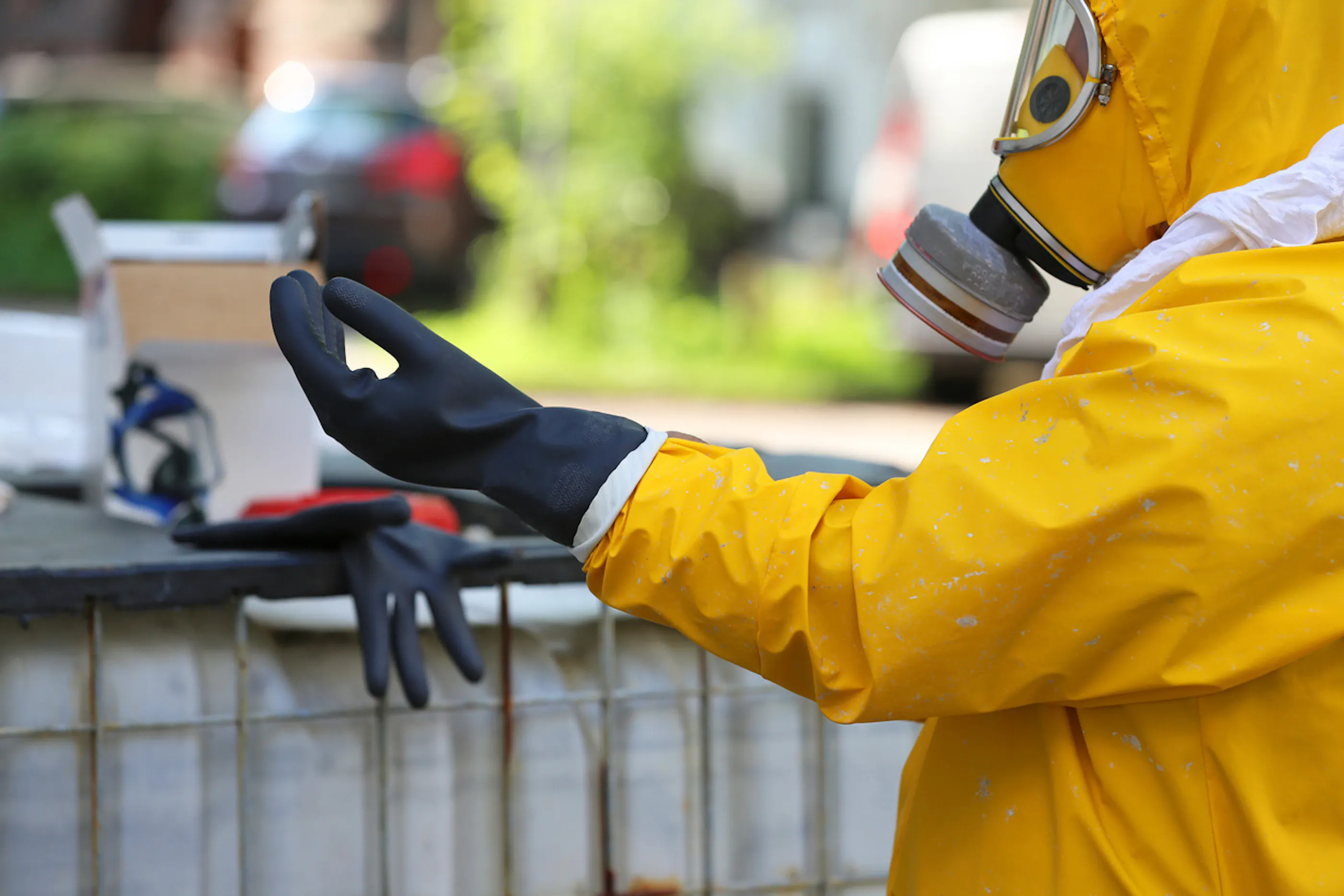 person in hazmat suit putting on gloves