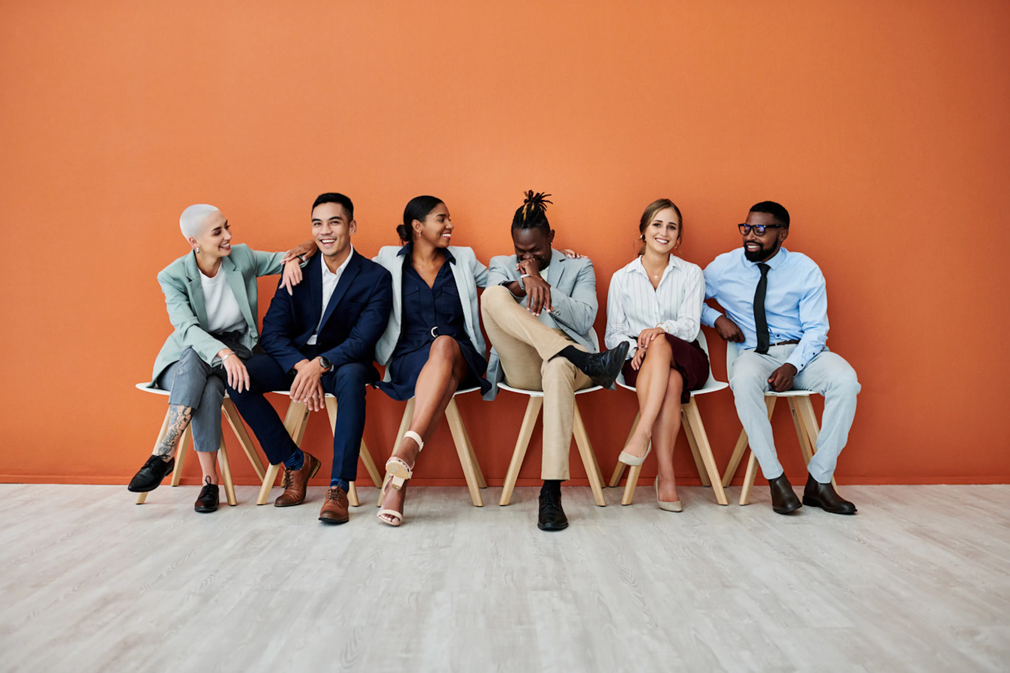 group of professionals sitting in chairs along an orange wall