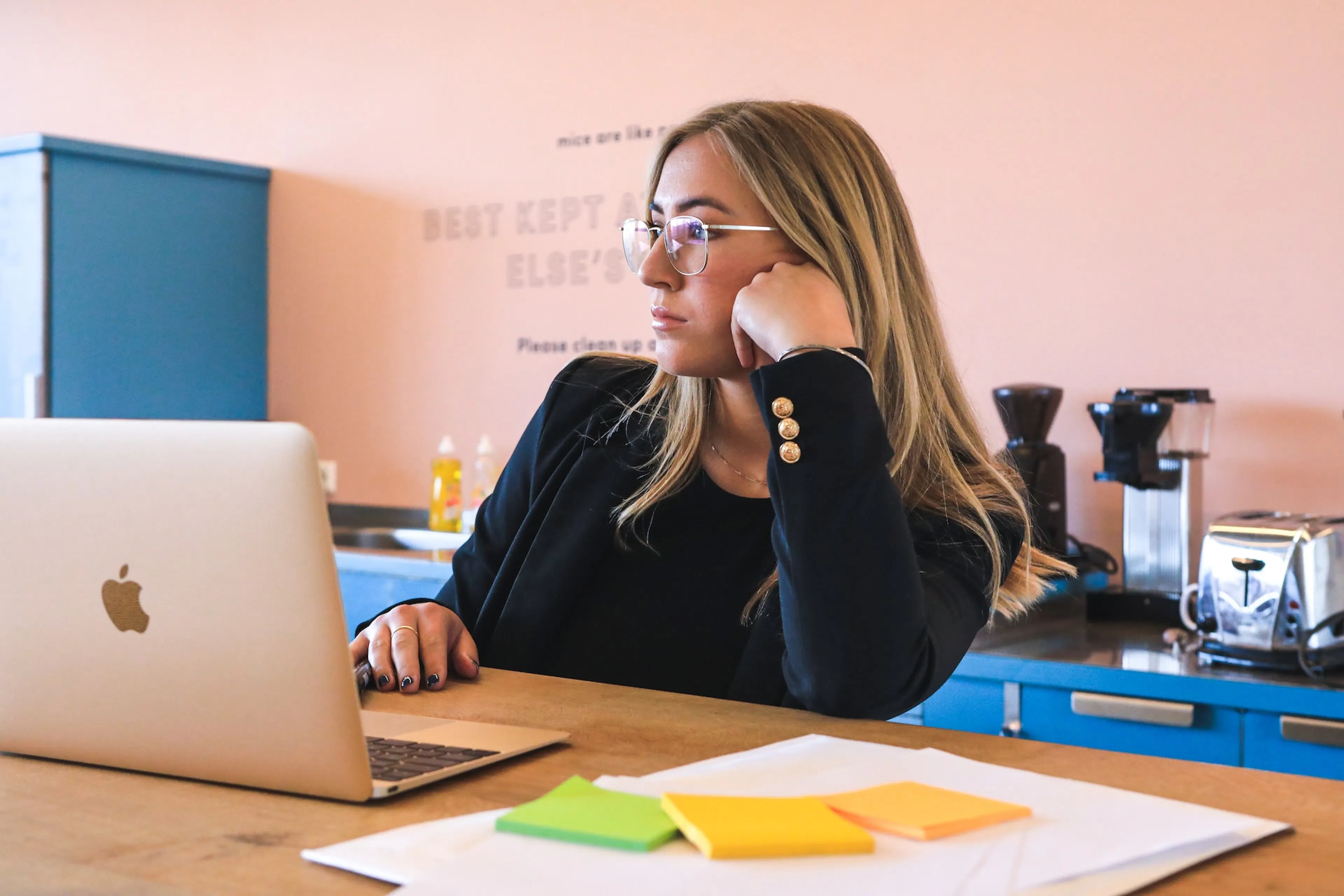 woman with glasses working on macbook laptop