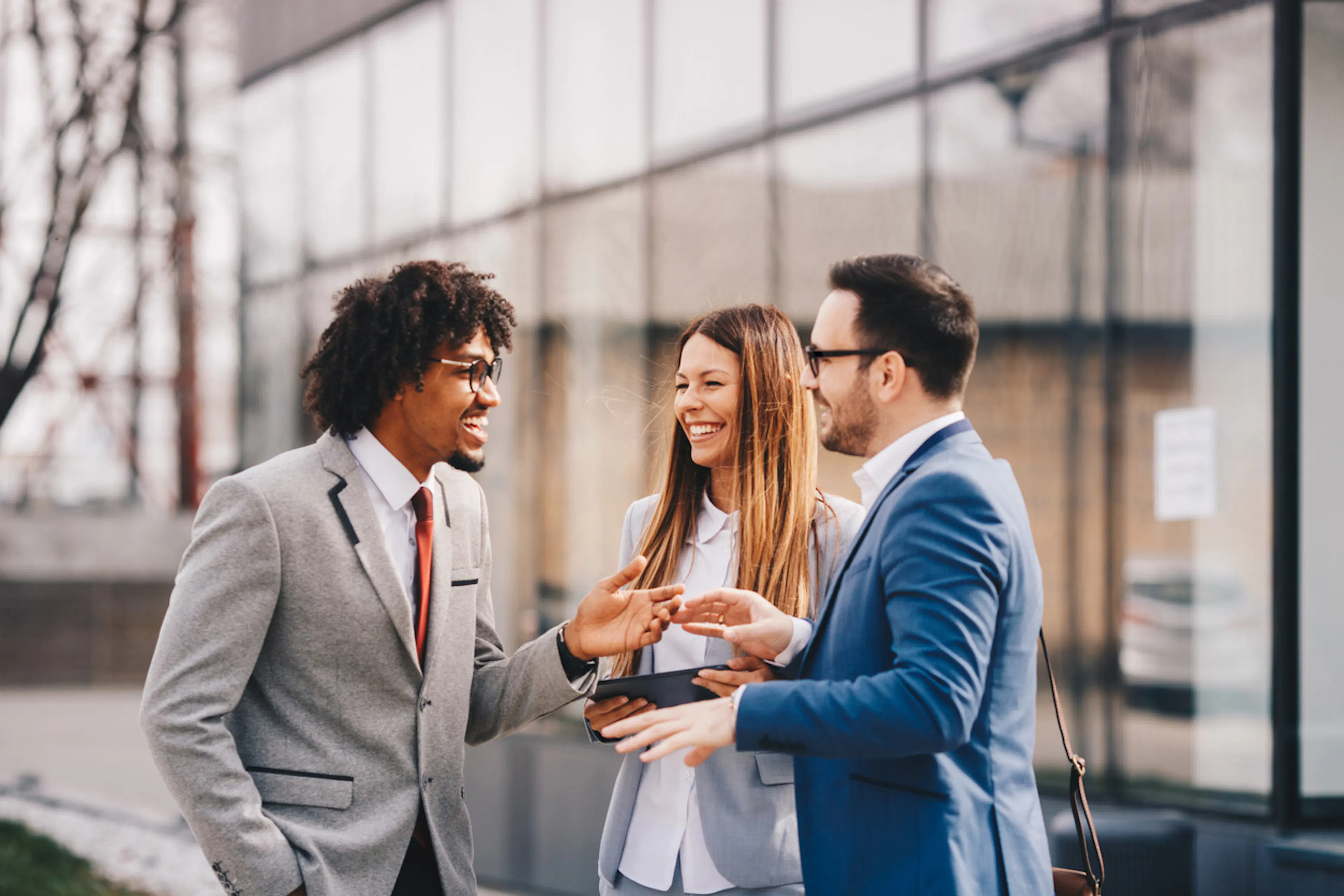 three professionals talking outside a building