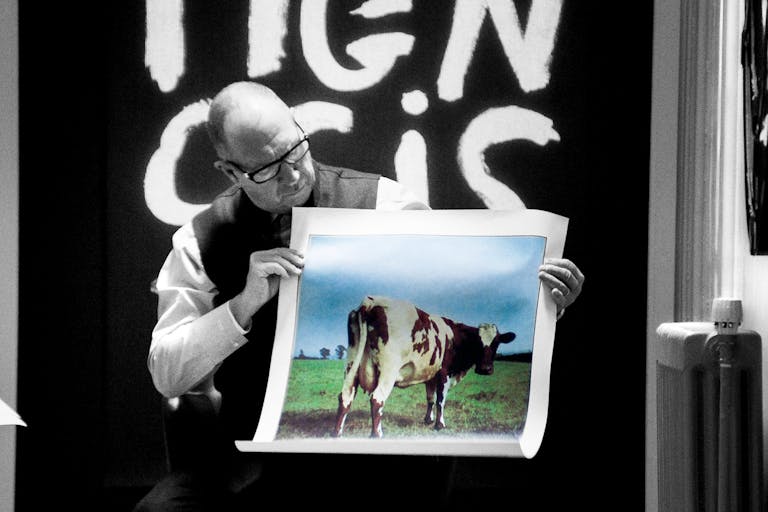 A man holds up a photo of a cow.