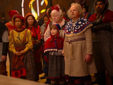A group of people, two older, a few younger, and a young boy, dressed in festive folk clothing 