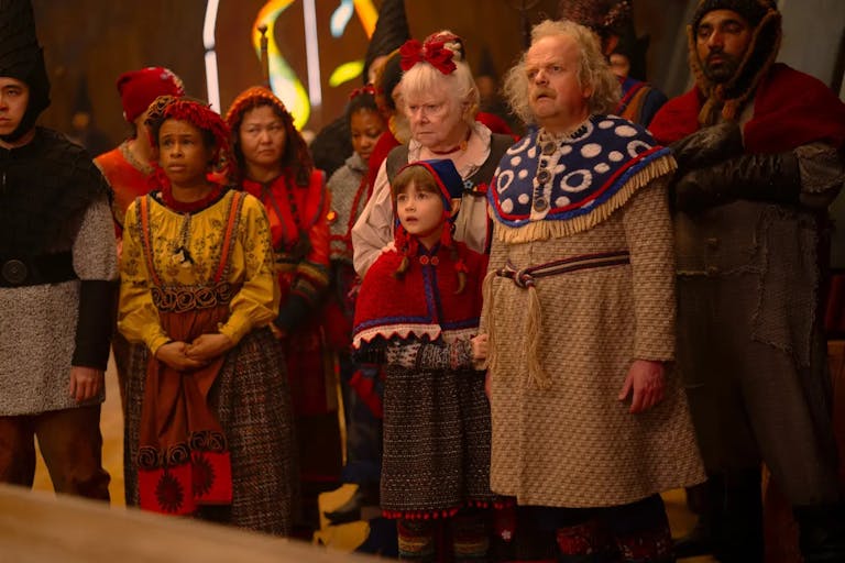 A group of people, two older, a few younger, and a young boy, dressed in festive folk clothing