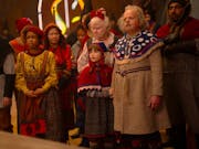 A group of people, two older, a few younger, and a young boy, dressed in festive folk clothing