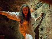 Woman in white dress in a candle-lit cave