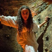 Woman in white dress in a candle-lit cave