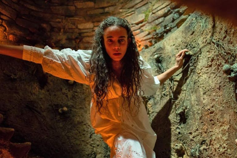 Woman in white dress in a candle-lit cave