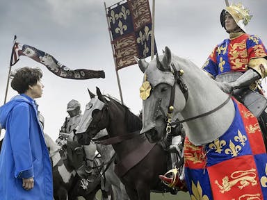 Woman in a blue raincoat looks up at a man riding a horse and dressed in medieval clothes