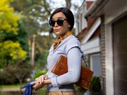 A woman with large dark sunglasses looking fashionable standing outside her home