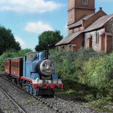 Stop motion animation of a blue train on the tracks riding through greenery past a quaint stone building