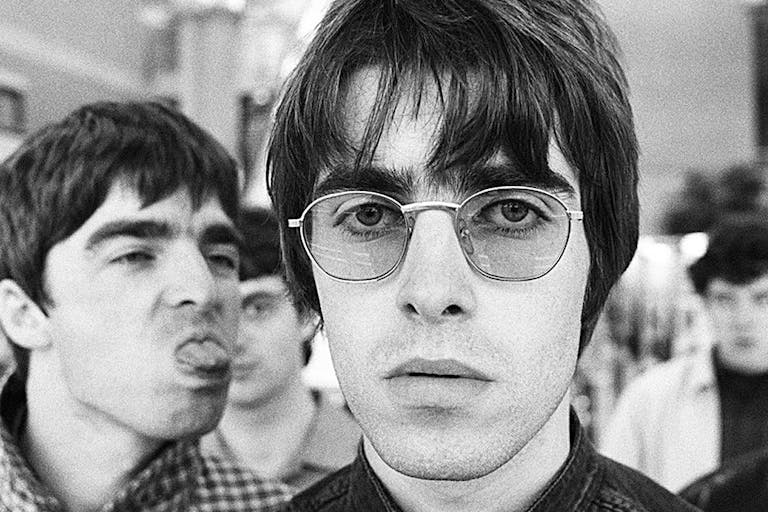 Black and white photo of young men, one in sunglasses, one sticking out his tongue. 
