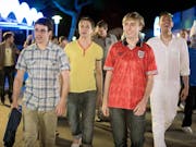 Four white older teen lads on holiday, one with a dark fake tan, walking in nightlife
