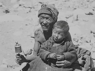 Black and white image of two local Himalayan people, a young boy sat on an old man's lap 