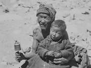 Black and white image of two local Himalayan people, a young boy sat on an old man's lap