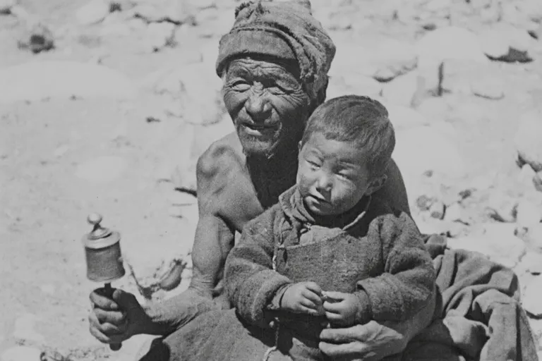 Black and white image of two local Himalayan people, a young boy sat on an old man's lap