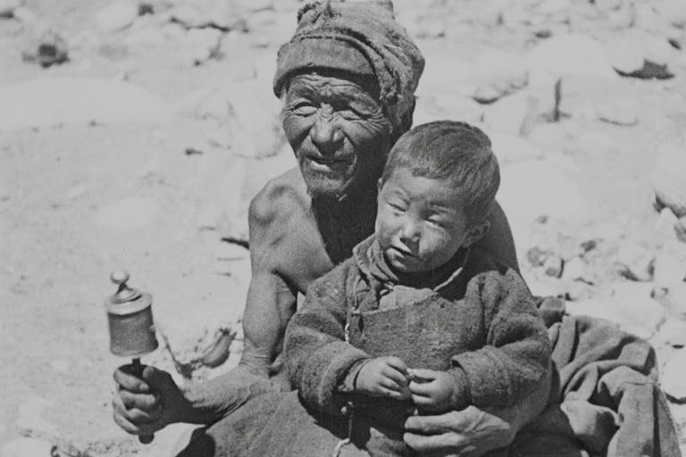 Black and white image of two local Himalayan people, a young boy sat on an old man's lap 