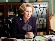 A comanding middle aged white woman with quaffed blonde hair sits at a desk