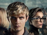 Young white boy with blond hair staring straight ahead, flanked by two white women either side looking serious