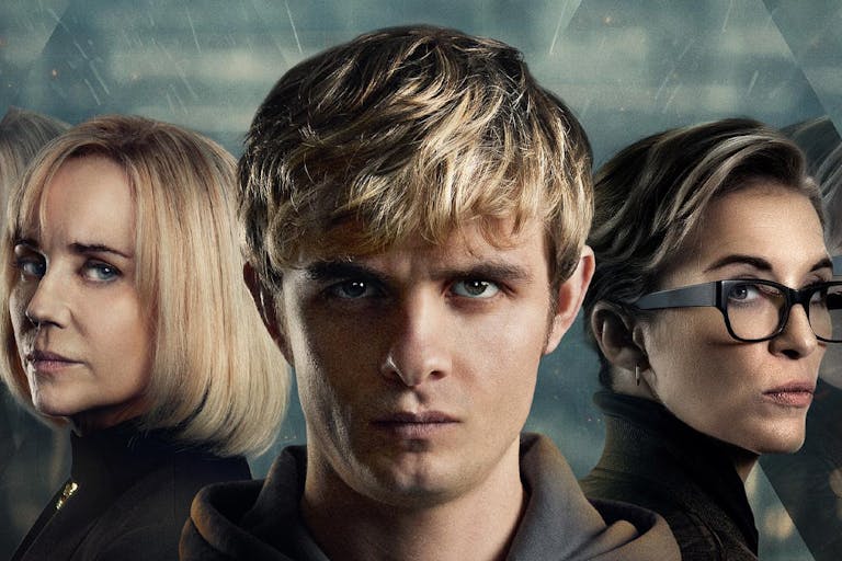 Young white boy with blond hair staring straight ahead, flanked by two white women either side looking serious