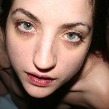 A young white woman with green eyes starring in the lens of the camera in a super close up