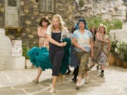 A group of women walking and dancing purposefully in Greece mid-song