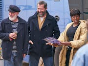 Two men and one woman stand talking and laughing