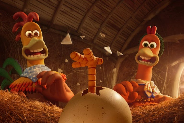 Stop motion animation of a male chicken and a female chicken looking surprised at a small chick's leg, kicking and breaking free of it's egg shell in the hen coop