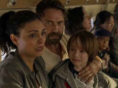 A man, woman and child, hold eachother on a plane, looking very scared. 