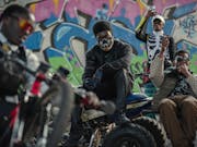 A group of young Black teens in trendy clothes in a colourfully graffitied underpass