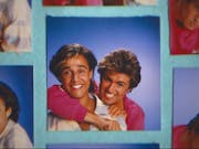 Two men in a playful embrace smiling widely at the camera