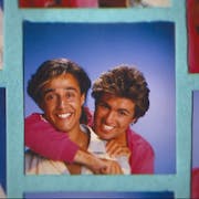 Two men in a playful embrace smiling widely at the camera