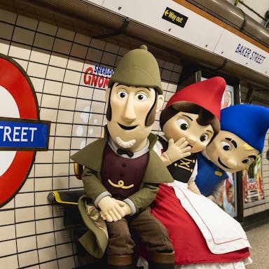 Animated scene of Sherlock Gnomes with two other gnomes, standing in the London Underground next to a sign for Baker Street. 