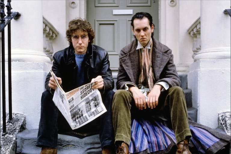 Two tall white men sitting on a London townhouse step looking sullen