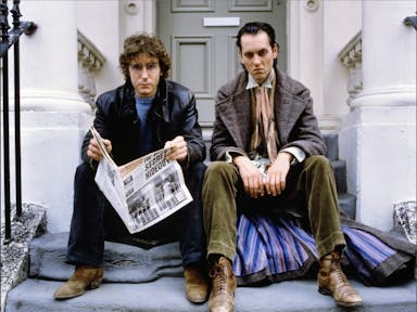 Two tall white men sitting on a London townhouse step looking sullen