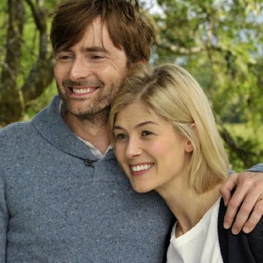 A white male and female middle aged couple embracing and smiling in a sunny garden