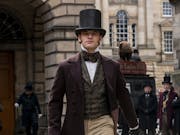 Man in a top hat and 19th century clothing walks through London.