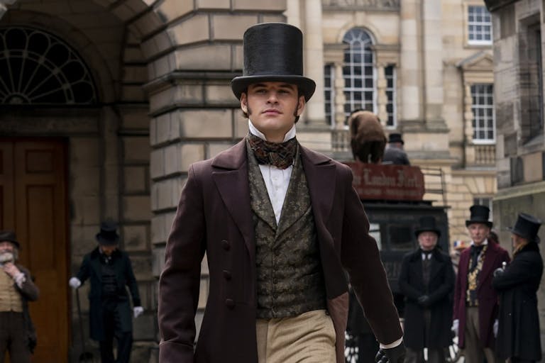 Man in a top hat and 19th century clothing walks through London. 