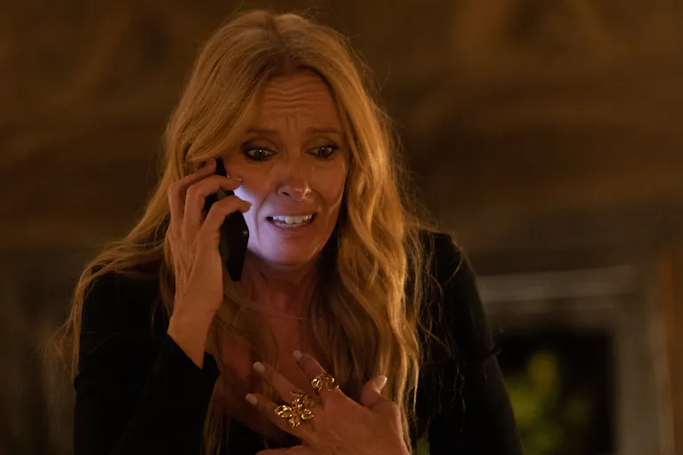 Blonde woman talking on a mobile phone with her hand to her chest, looking very worried