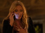 Blonde woman talking on a mobile phone with her hand to her chest, looking very worried