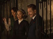 Two women and one man stand in a dark, haunting room