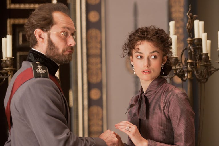 A white man in Russian empirical clothing standing with a white woman in aristocratic clothing in a grand house