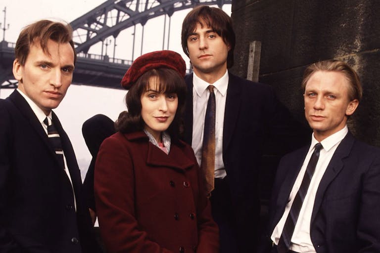 Three white men in suits and a white woman in a red velvet hat and coat