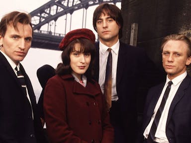 Three white men in suits and a white woman in a red velvet hat and coat 