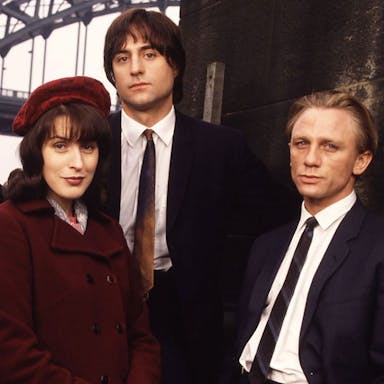 Three white men in suits and a white woman in a red velvet hat and coat 