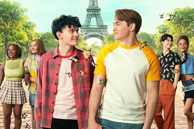 Two male teens holding hands, looking lovingly in each others' eyes, flanked by their friends with the Eiffel Tower in the background