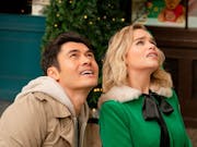 Blonde woman in a festival green top and man in beige hoody sit next to one another looking up at the sky.