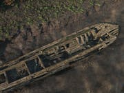 Reconstructed image of a long wooden boat stuck in the mud with the water drained away